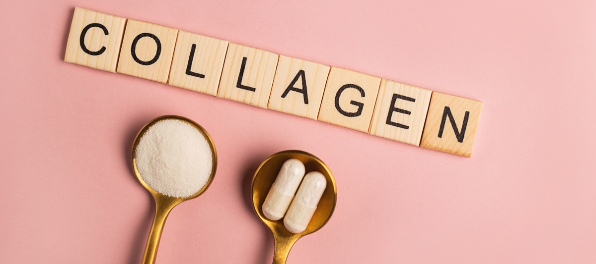 Der Schriftzug „Collagen" aus Holzbuchstaben auf rosa Untergrund, darunter zwei goldene Löffel mit Kollagenpulver und Kapseln.