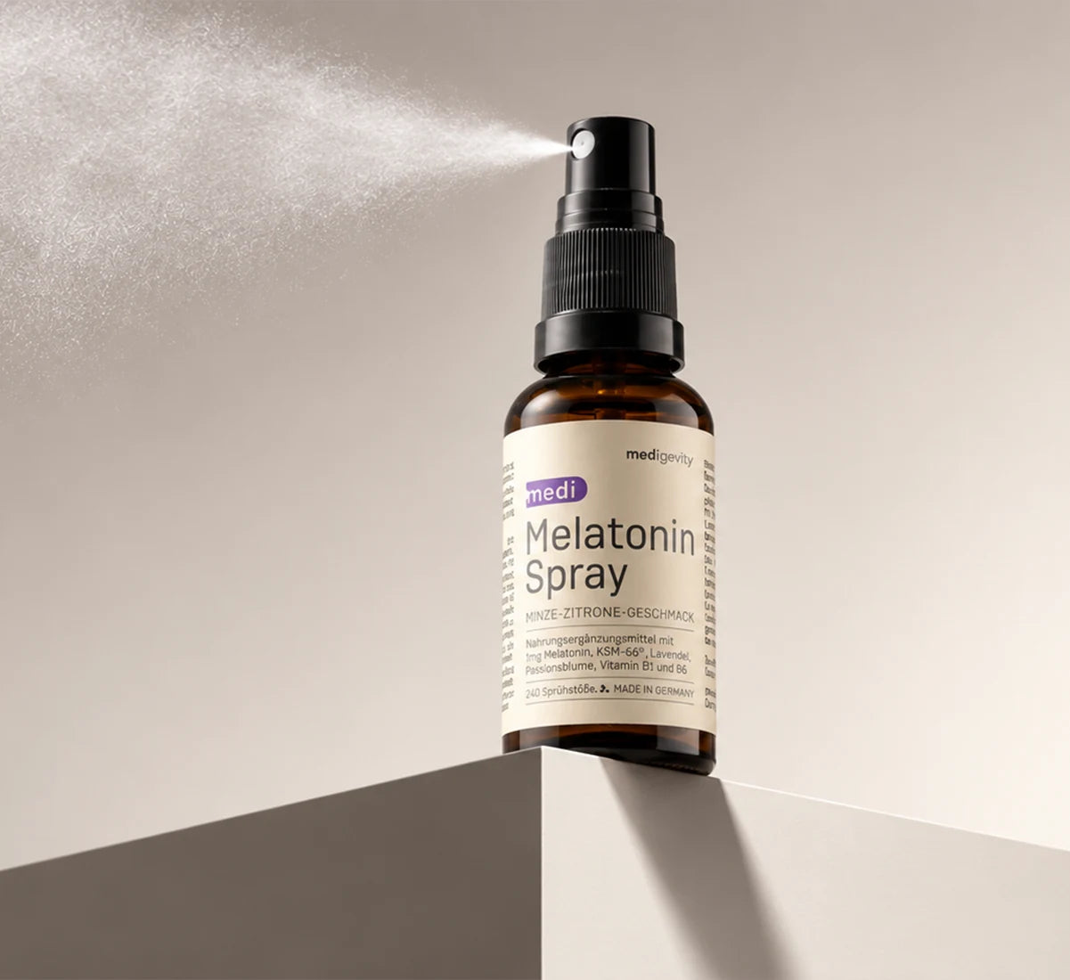 medi Melatonin Spray Flasche auf einer Kante platziert, sprüht feinen Nebel vor beigefarbenem Hintergrund