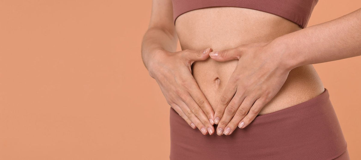 Frau formt mit ihren Händen ein Herz über dem Bauch – Symbolbild für die Rolle von Vitamin C bei der Eisenaufnahme