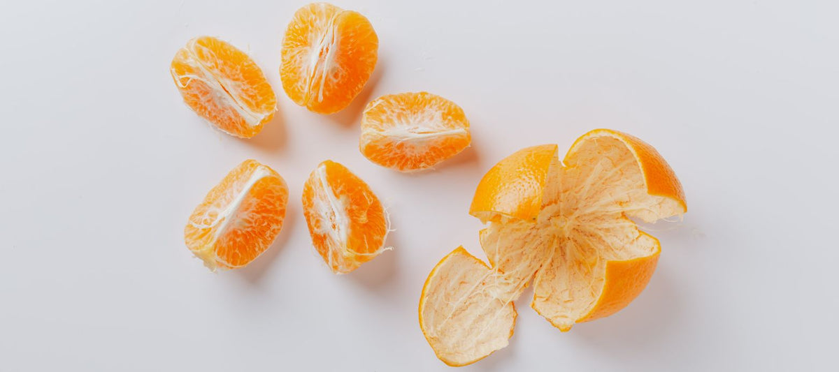 Aufgeschnittene und geschälte Orangenspalten von oben fotografiert auf weißem Untergrund – Hintergrundbild für den Wissenschaftsartikel zu Vitamin C